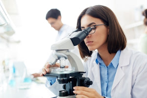 Scientist examining samples under a microscope in a lab focused on TB-500 peptide latest research 2025